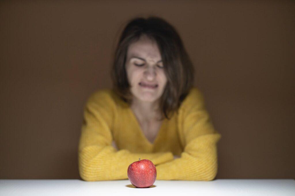 An apple on the table and unfocused woman behind