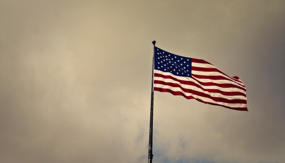united states flag in front of grey skies