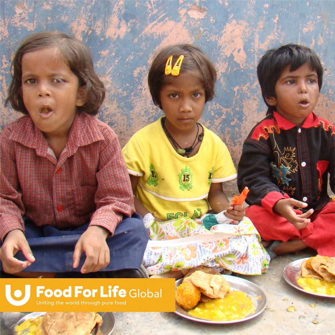 Three children sitting while eating food