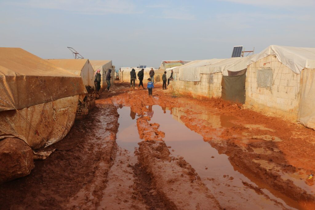 people walking between the refugee tents in a refugee camp