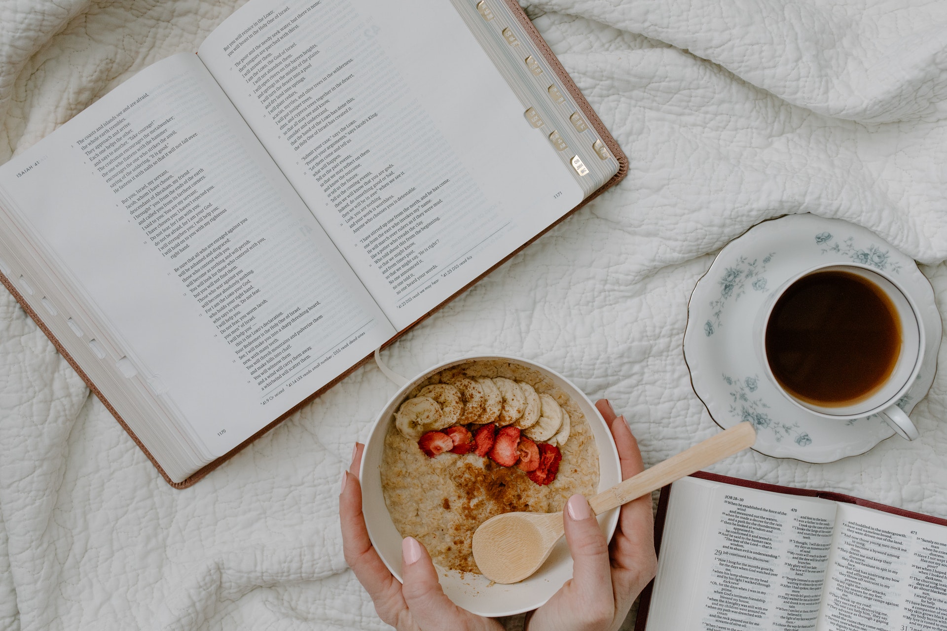 A bowl of oatmeal with coconut milk next to a cup of coffee and the Bible