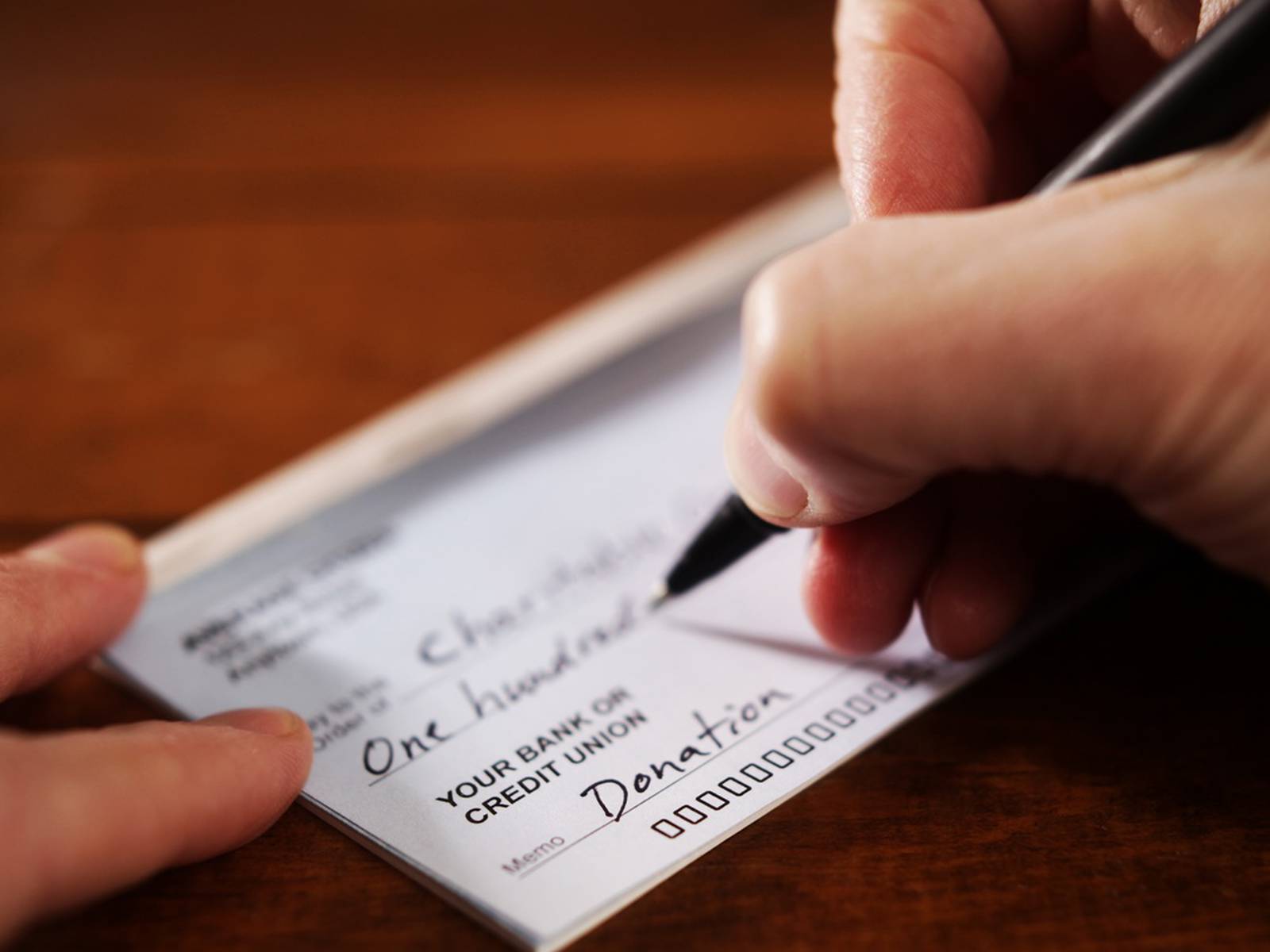 Person writing check donation to charity