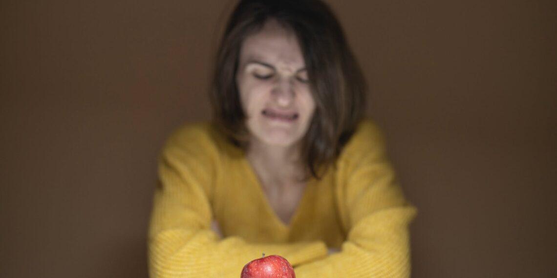 Wat is voedselonzekerheid precies? Een appel op de tafel en ongericht vrouw achter