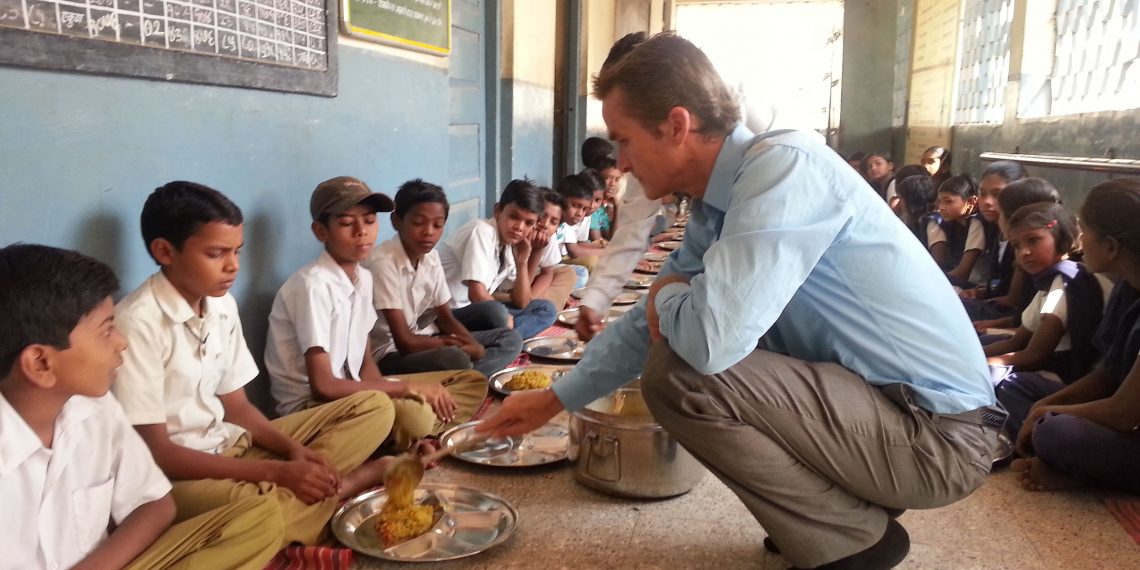 Top Five Non-Profit Podcasts For Aspiring Social Entrepreneurs Man giving food to children